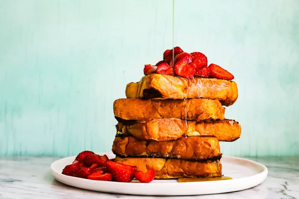 A stack of french toast piled high with strawberries.