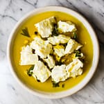 Chunks of marinated feta in olive oil and herbs.