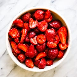 A big bowl of cut strawberries.