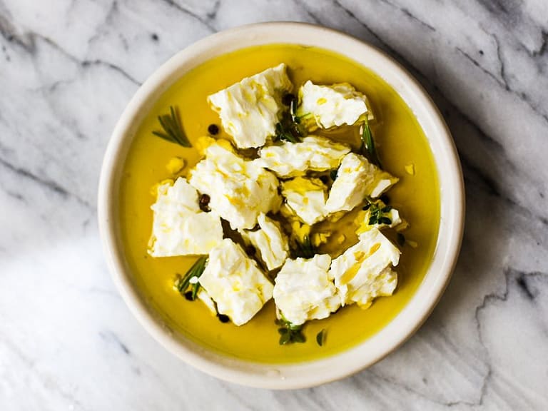 Chunks of marinated feta in olive oil and herbs.